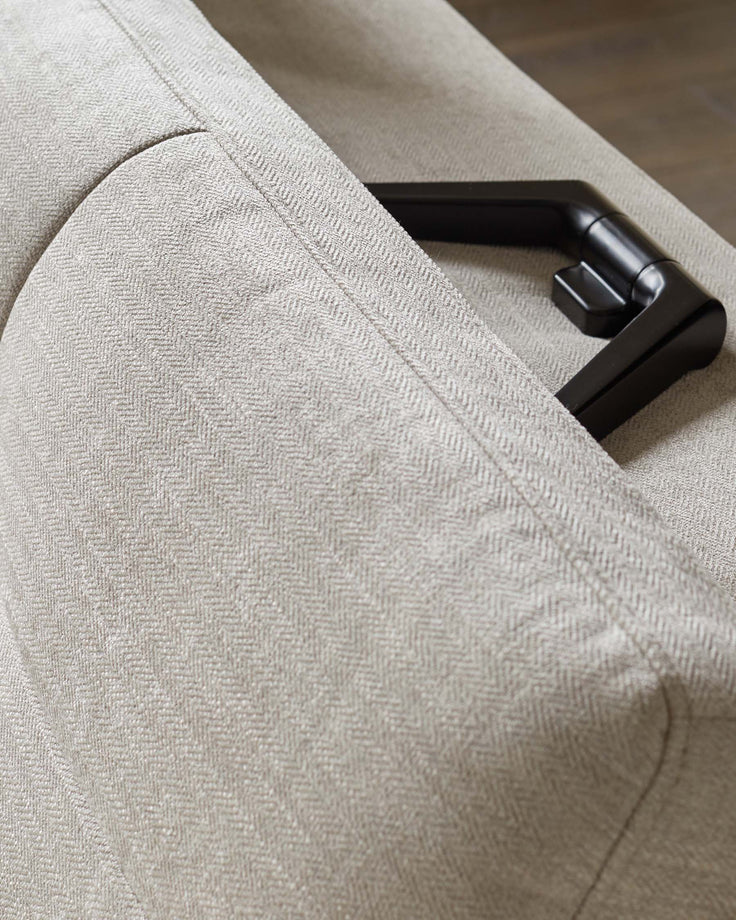 Close-up of a neutral-toned sofa, showcasing its herringbone pattern and the armrest detail.