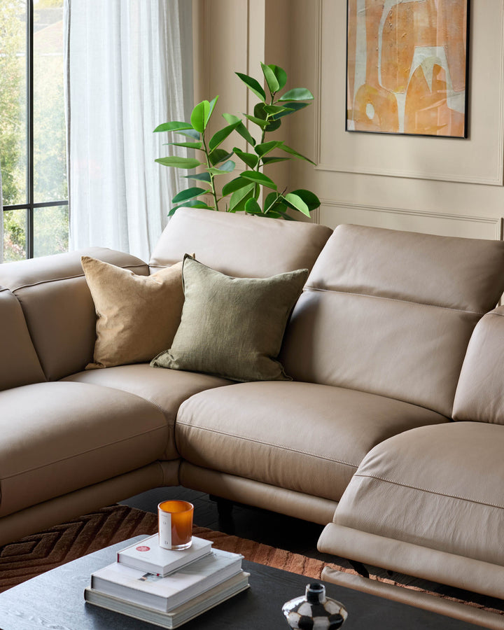 Connor left-hand corner chaise sofa in natural leather, styled in a bright living room with decorative pillows and a plant.