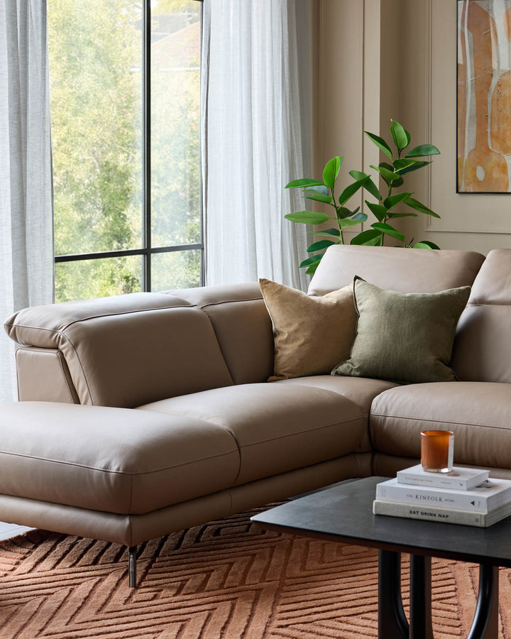 Connor left-hand corner chaise sofa in natural leather, displayed in a bright living room setting with cushions and plants.