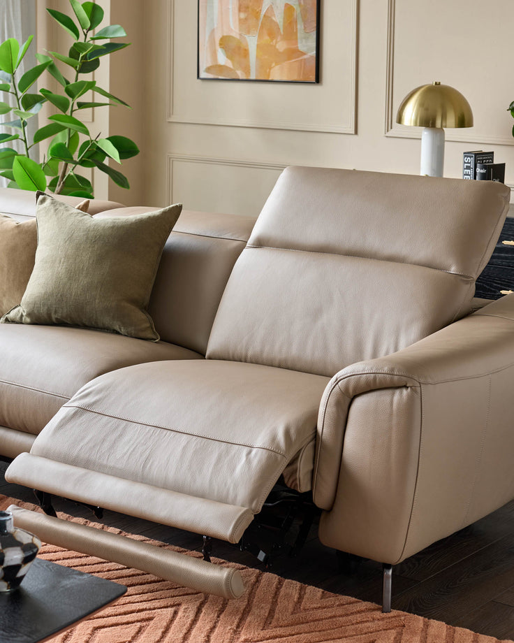 Beige leather corner chaise sofa with extended footrest, angled view showing relaxed seating position and modern design.