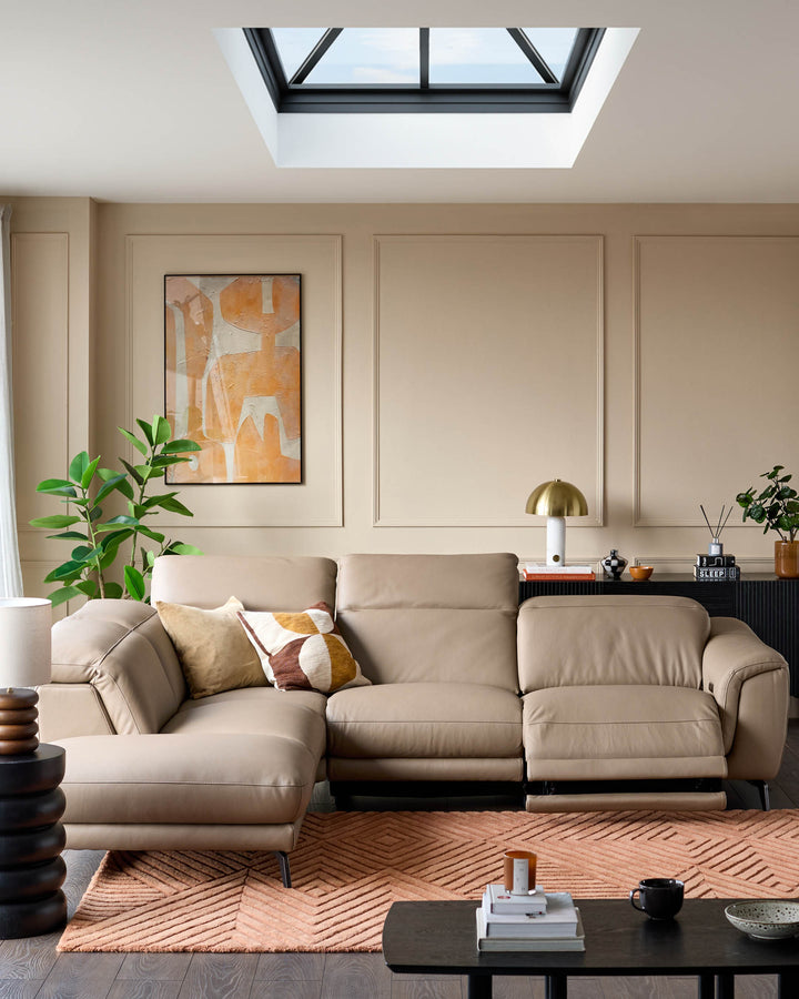 Connor left-hand corner chaise sofa in natural leather, shown in a modern living room with neutral décor and skylight.