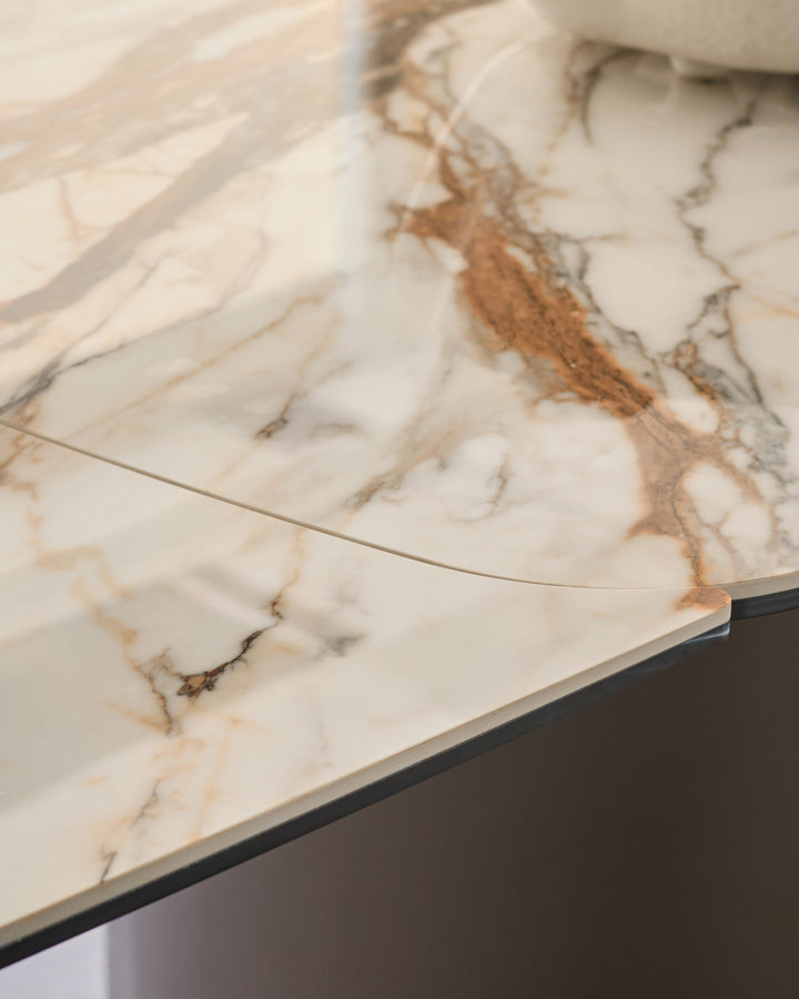 Cortona dining table detail showing marble-effect ceramic top with brown and Grey veining and black metal base edge.