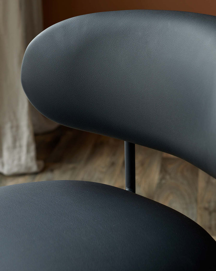 Close-up of a sleek, dark grey chair with textured upholstery, highlighting modern design and comfort.