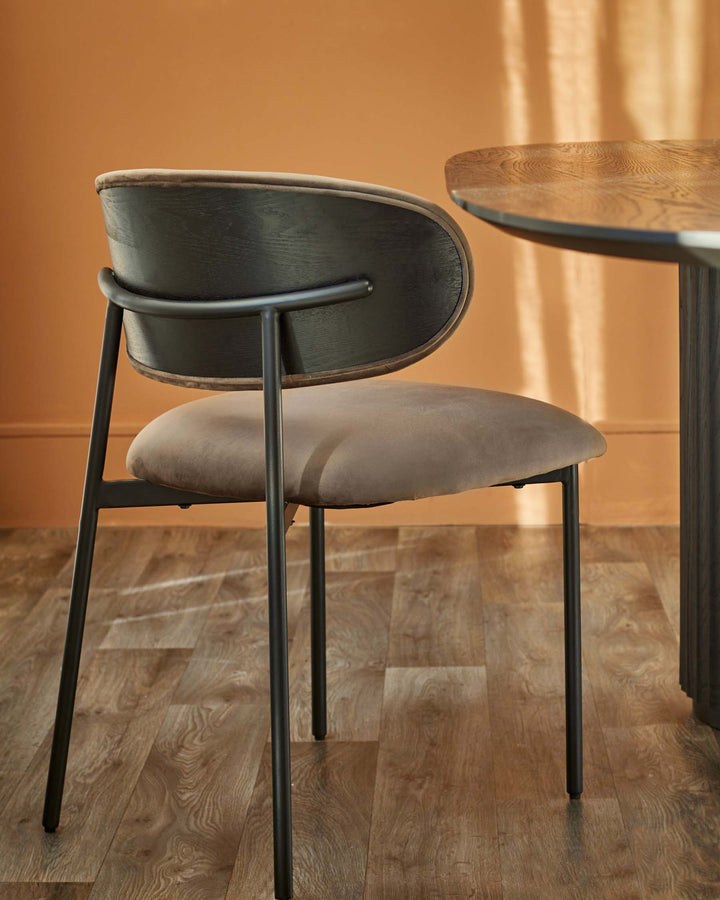 A stylish chair with a curved back and seat, complemented by a round wooden table, showcasing modern furniture design.