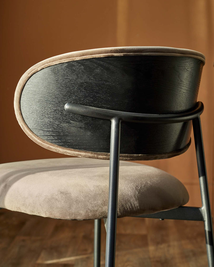Close up of a modern chair with a dark wood back and brown upholstered seat, showcasing its sleek design and comfortable feel.