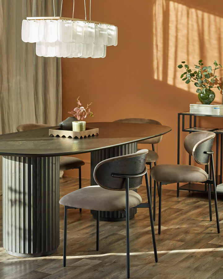 A stylish dining set featuring a modern table with brown chairs and a unique layered chandelier.