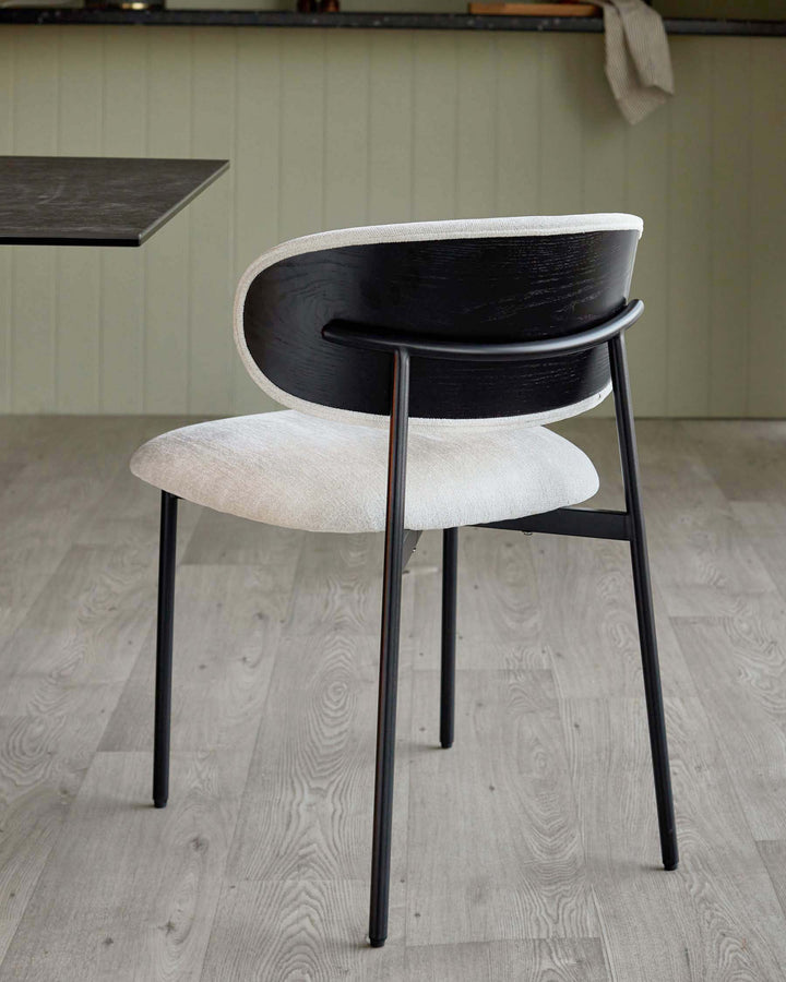Elegant black and cream upholstered dining chair with sleek metal frame, adding style to any modern dining area.