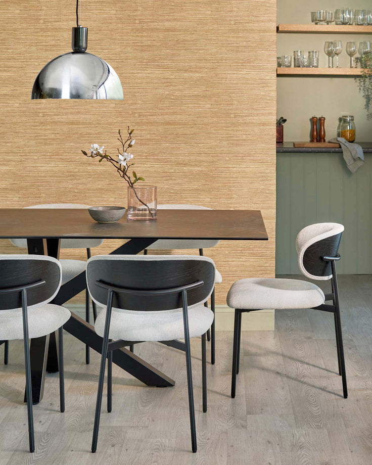 A dining room featuring a table with a statement base and modern chairs. A stylish lighting fixture hangs above.