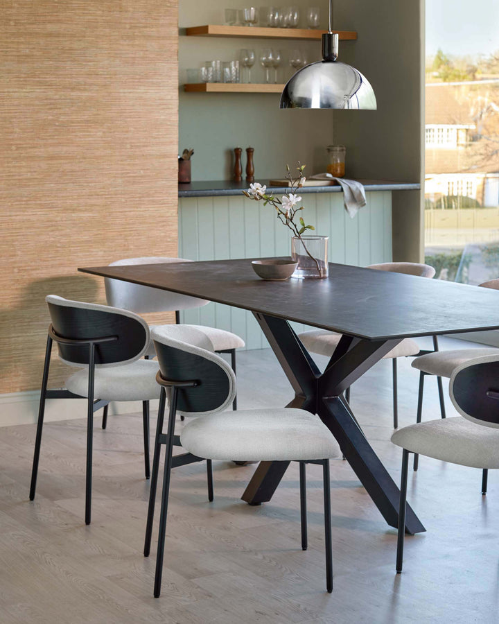 A modern dining table and chairs are arranged in a stylish dining room setting.