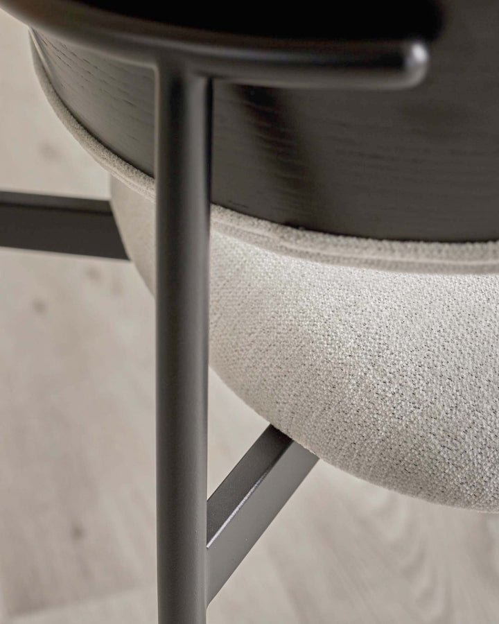 Close-up of a chair with light grey upholstery, dark wood and grey metal legs. Minimalist design.