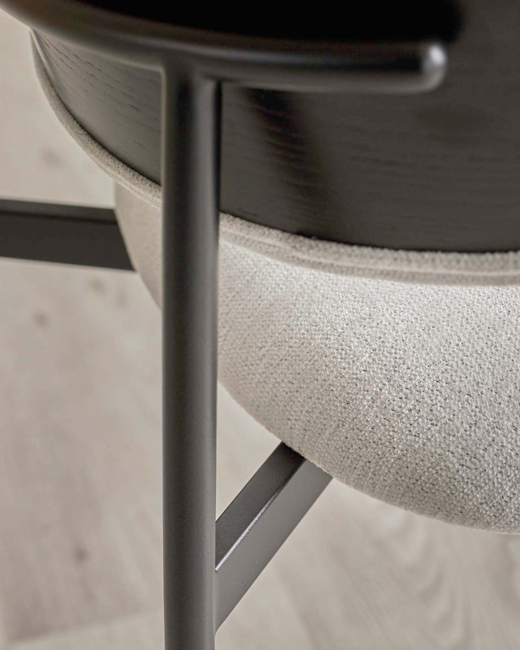 Close-up of a chair with light grey upholstery, dark wood and grey metal legs. Minimalist design.