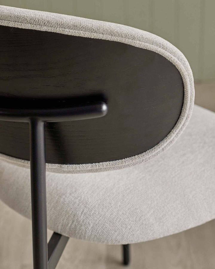 Close up of a grey chair with a curved upholstered back and sleek black frame. Modern design for stylish living spaces.