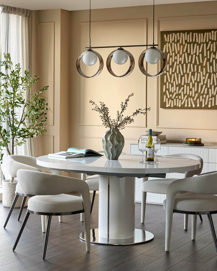 Gloss white round extending dining table with pedestal base in modern dining room setting.
