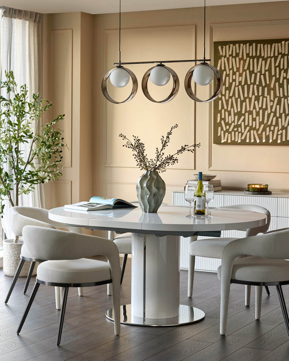 Gloss white round extending dining table with pedestal base in modern dining room setting.