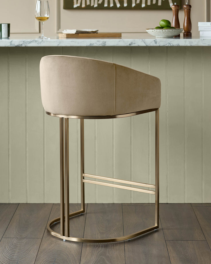 Dakota velvet barstool in champagne with curved backrest and brass metal frame, shown from rear angle.