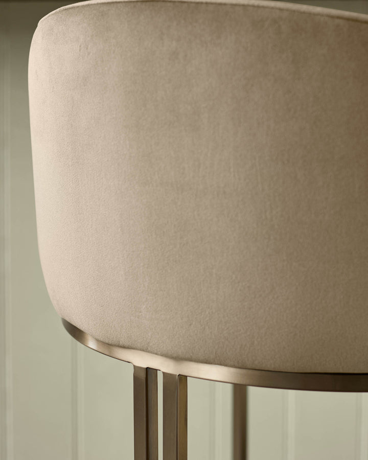 Dakota velvet barstool in champagne with brass base, shown in close-up detail highlighting the soft upholstery texture.