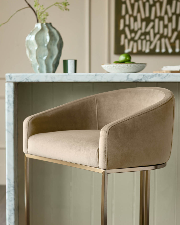 Dakota velvet barstool in champagne with brass frame, shown in styled interior setting.