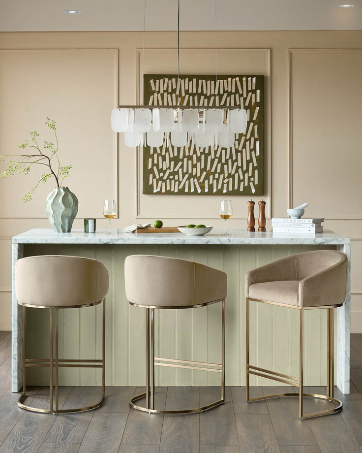 Dakota velvet barstool in champagne with brass frame, shown in kitchen setting at marble counter.