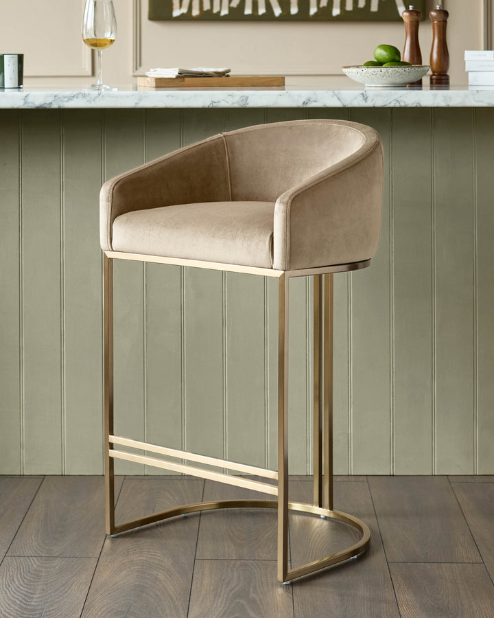 Dakota velvet barstool in champagne with brass frame and footrest, positioned at kitchen counter.