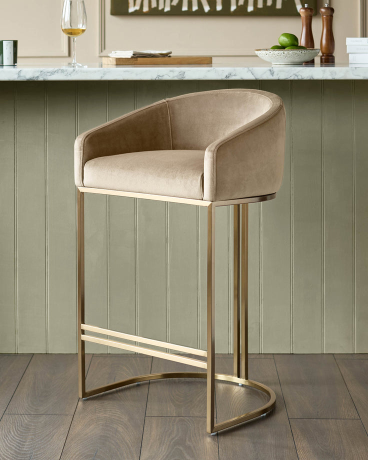 Dakota velvet barstool in champagne with brass frame and footrest, positioned at kitchen counter.