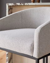 Dakota bar stool in natural fabric with curved backrest and dark metal base, shown in close-up side view.