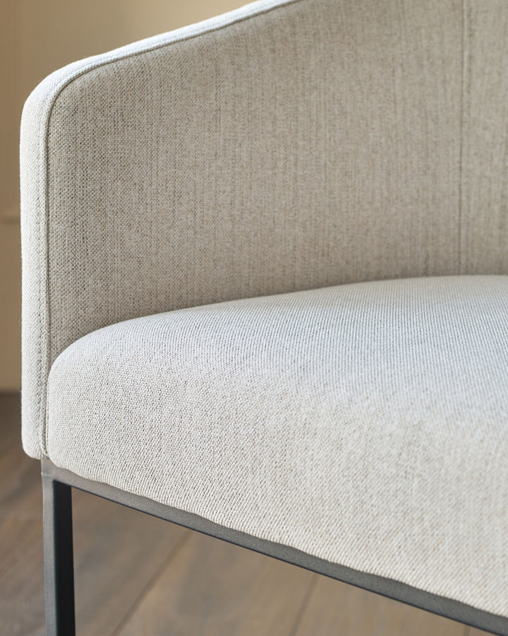 Dakota dining chair in natural fabric, close-up side view showing curved backrest and seat detail.