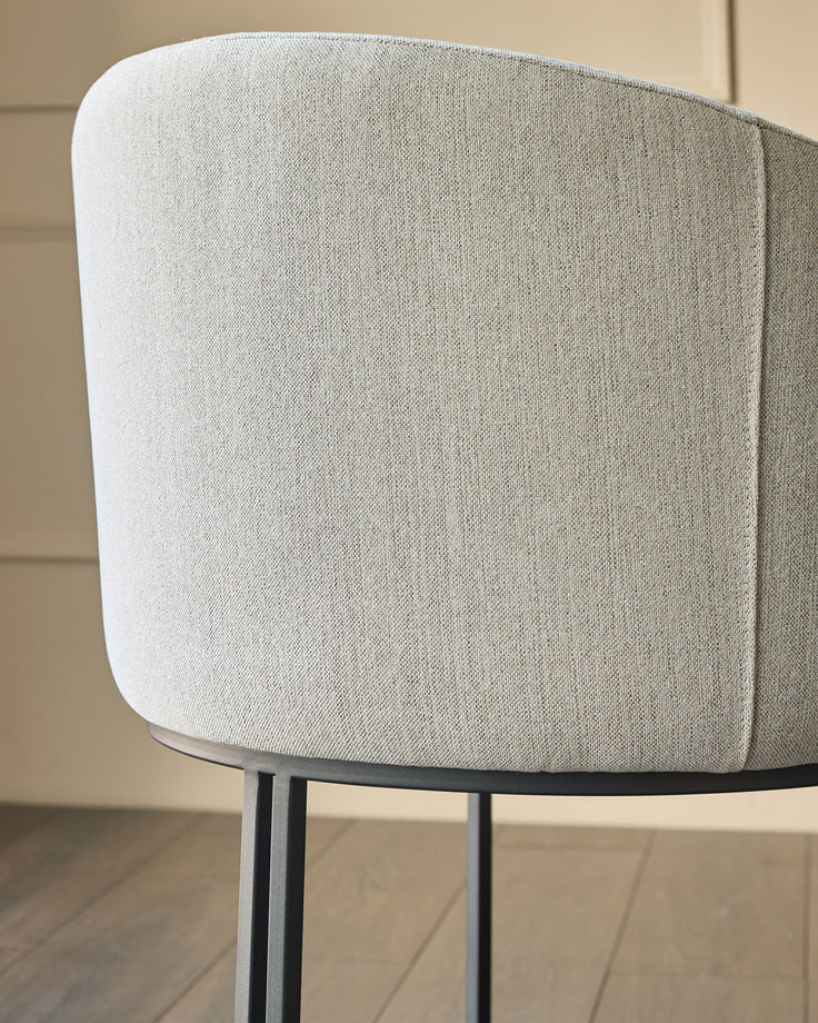 Dakota dining chair in natural fabric, shown from rear angle displaying curved backrest and metal legs.