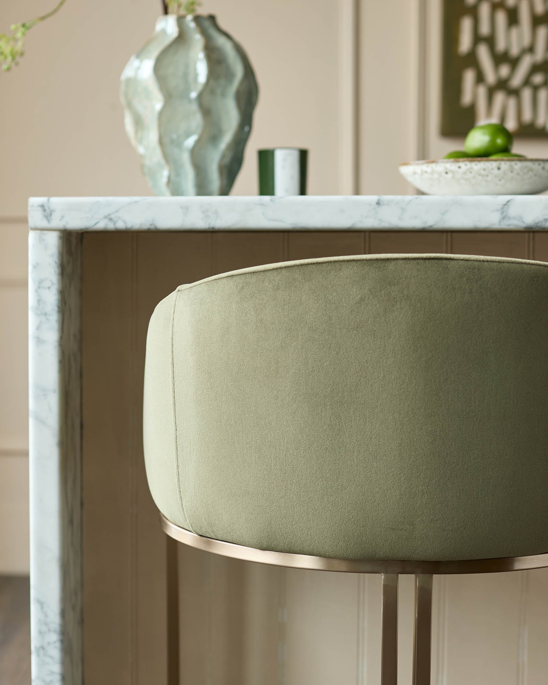 Dakota bar stool in olive green velvet with brushed gold footrest, shown at marble countertop.