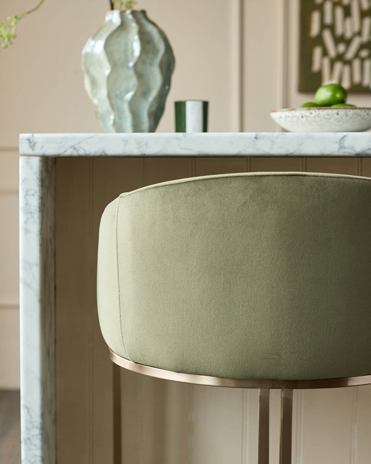Dakota bar stool in olive green velvet with brushed gold footrest, shown at marble countertop.
