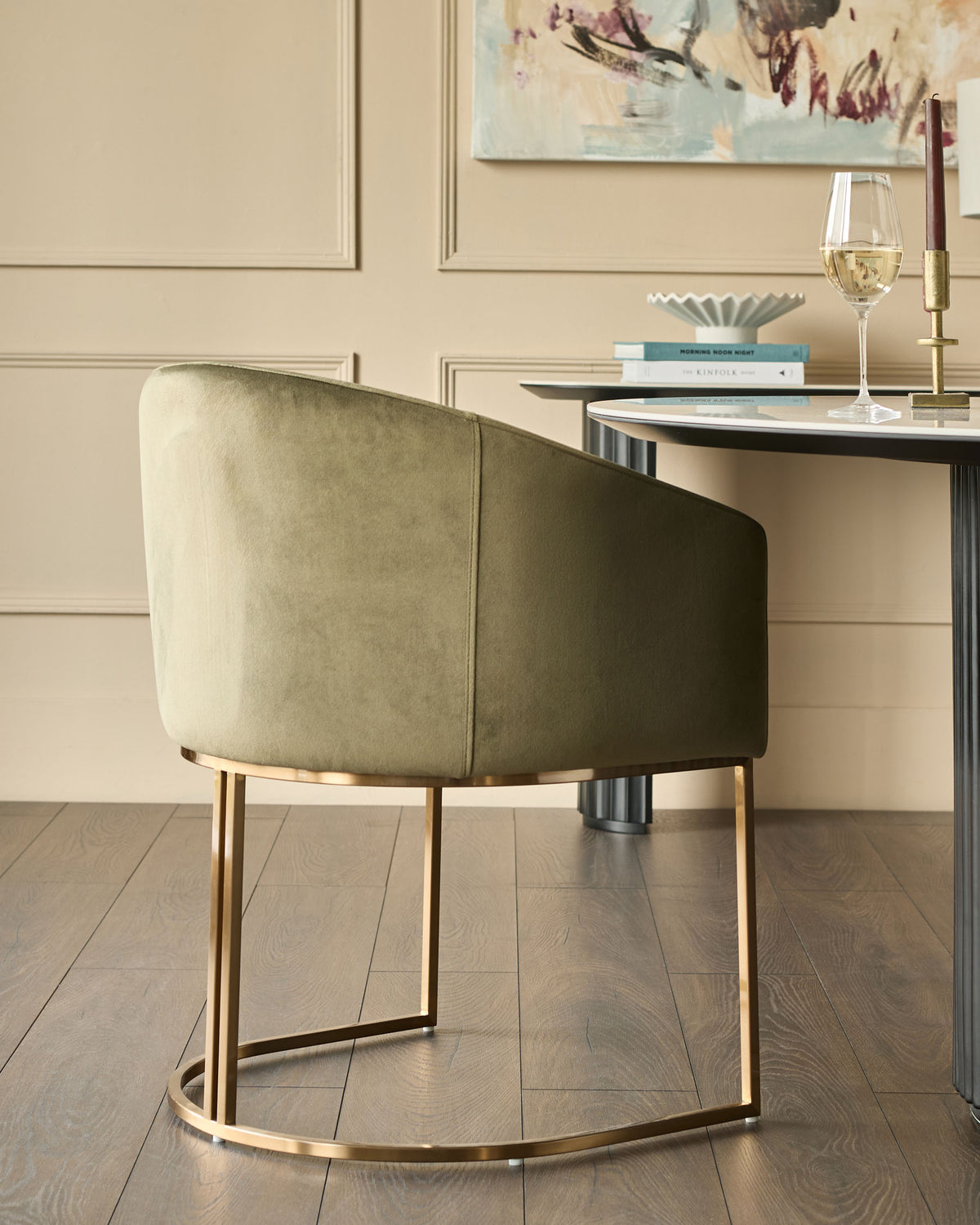 Dakota dining chair in olive green velvet with curved back, brass legs, shown at desk in modern room setting.