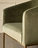 Dakota dining chair in olive green velvet with curved backrest and wooden legs, side view detail.