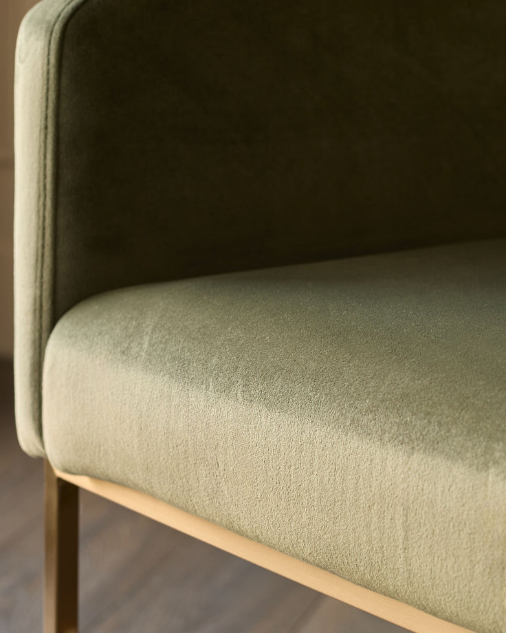 Dakota dining chair in olive green velvet, side profile showing curved backrest and seat with natural wood base.