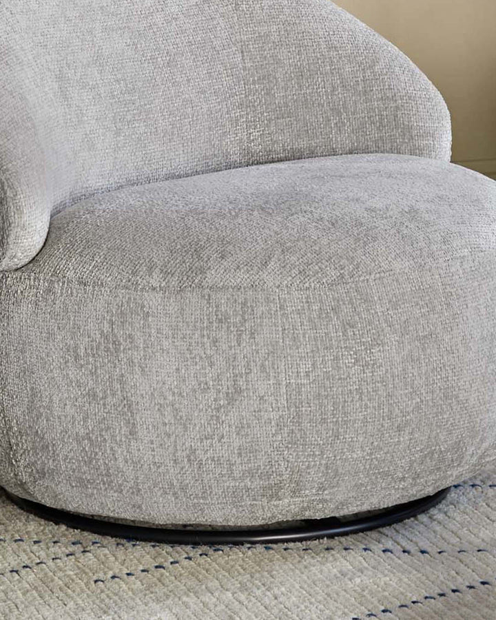 Daphne Weave Swivel Accent Chair in light grey, showing curved seat and back with black swivel base on area rug.
