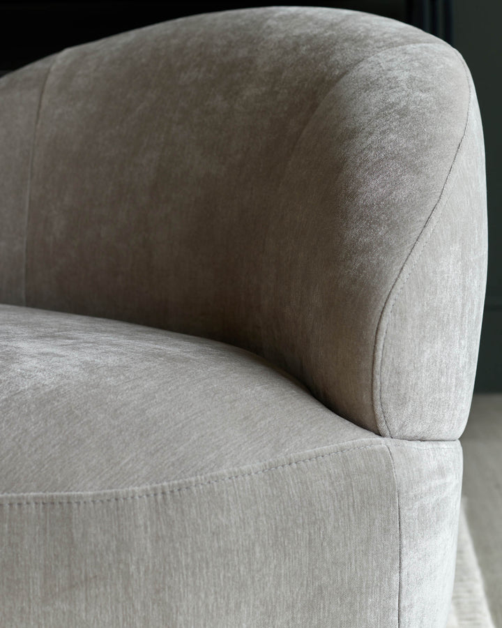 Close-up of a stylish, curved, upholstered sofa, showcasing its plush fabric and elegant design. Ideal for modern living spaces.