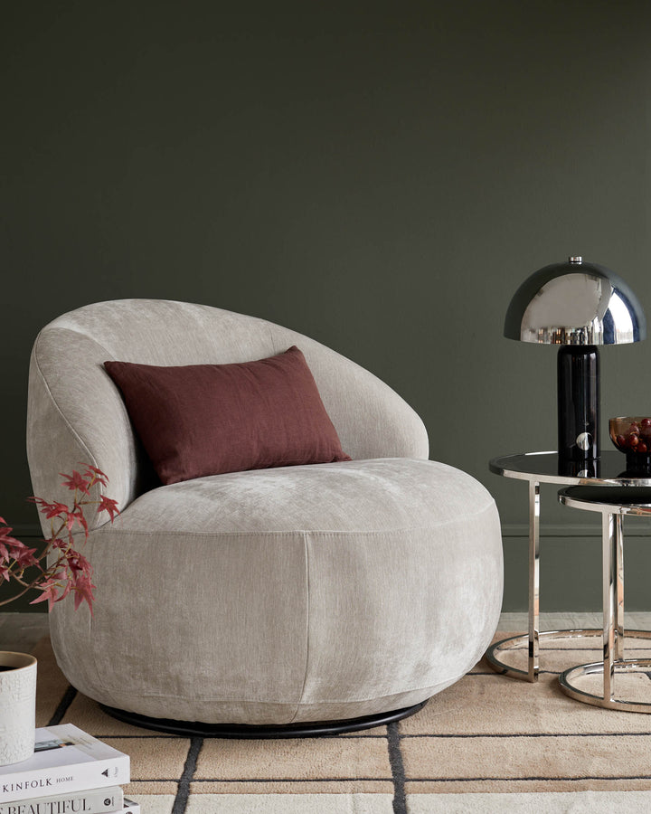 Stylish room with a modern armchair, table lamp and side tables. A luxurious and inviting furniture arrangement.