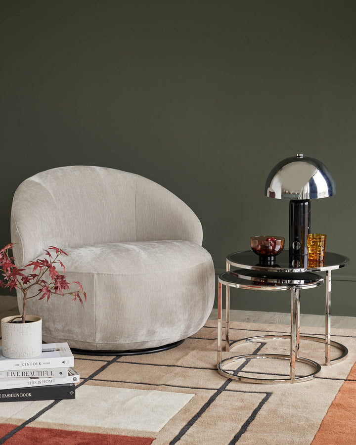 Stylish living room furniture featuring a neutral armchair, nesting tables and a statement lamp.