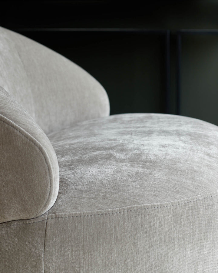 Close-up of a stylish, neutral-toned armchair with a soft, textured fabric. Perfect for adding comfort to any living space.
