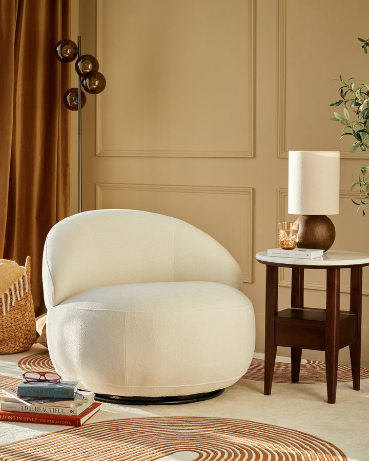 Stylish bouclé swivel chair next to a mid-century modern side table and floor lamp, creating a cosy and inviting living space.