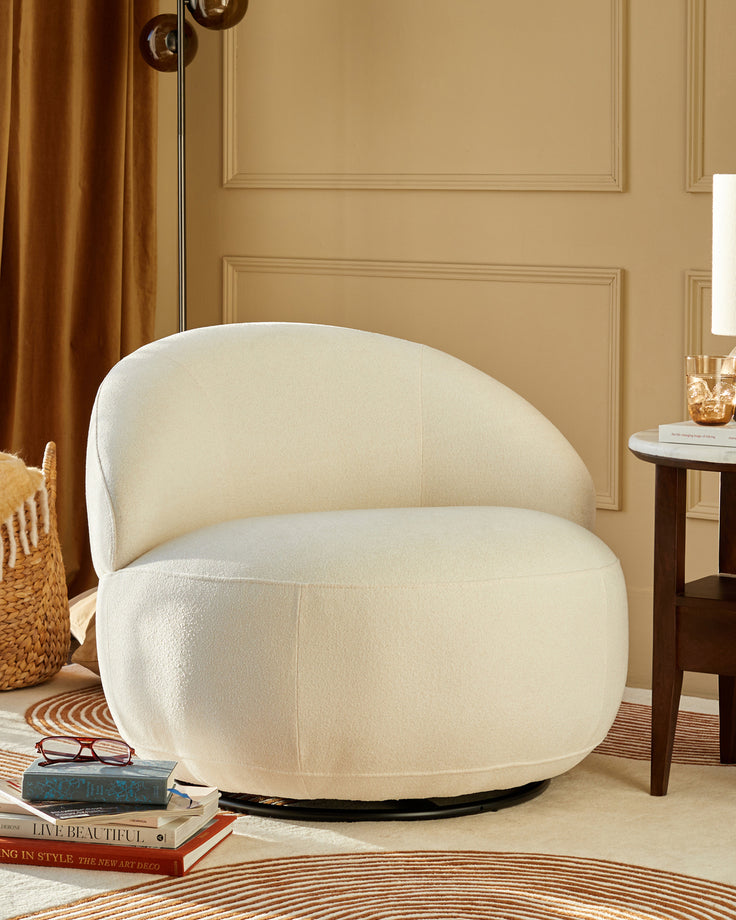A modern, cream-coloured swivel chair takes centre stage.  A round side table and books complete the stylish interior scene.