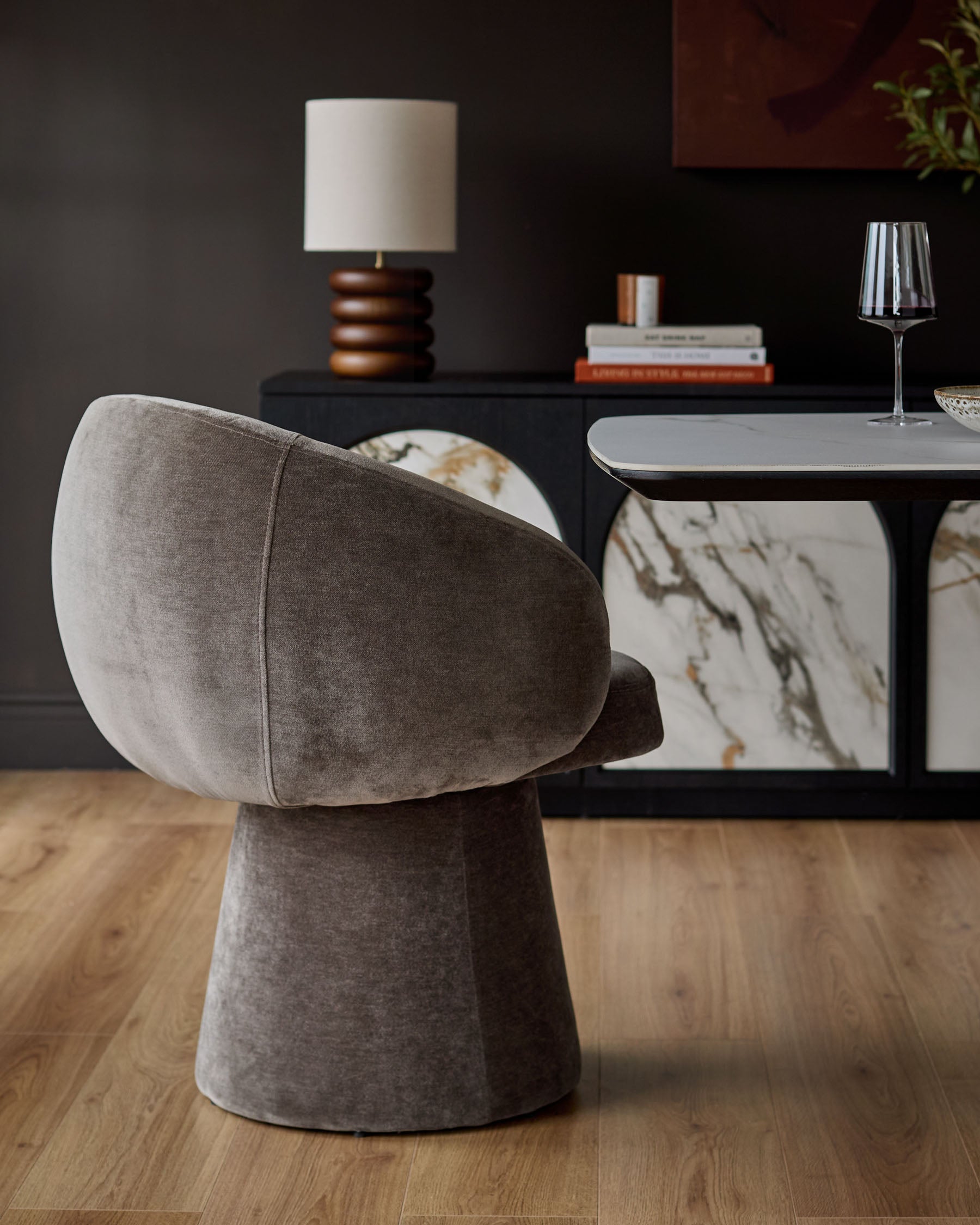 Darcy swivel dining chair in mocha fabric, shown from rear angle on wooden floor in modern dining setting.