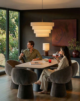 Mocha fabric swivel dining chair with curved barrel shape, shown in dining room setting at table with couple.