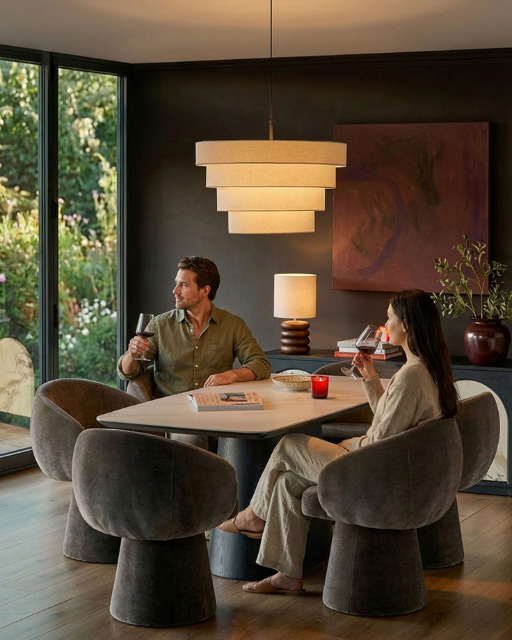 Mocha fabric swivel dining chair with curved barrel shape, shown in dining room setting at table with couple.
