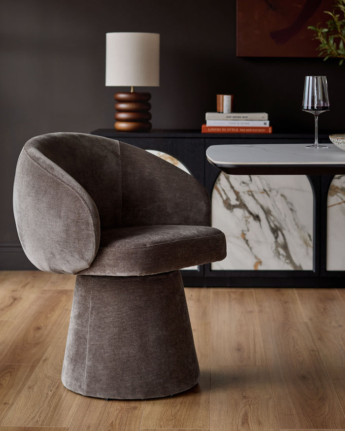 Darcy swivel dining chair in mocha fabric with curved backrest and cylindrical base, shown in modern room setting.