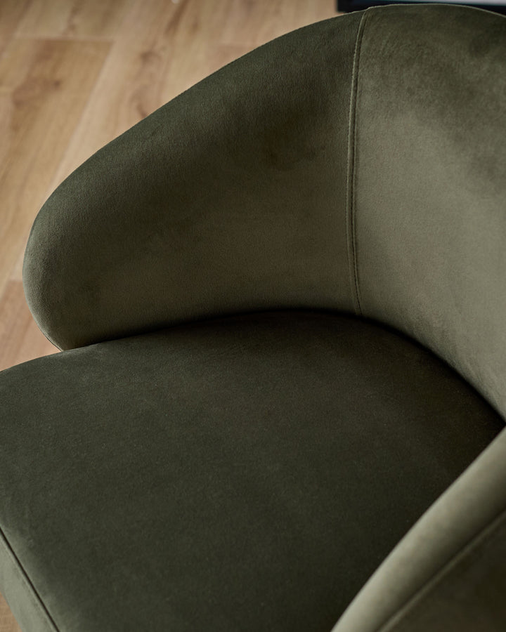 Darcy swivel dining chair in olive green velvet, showing curved backrest and seat from above angle on wooden floor.