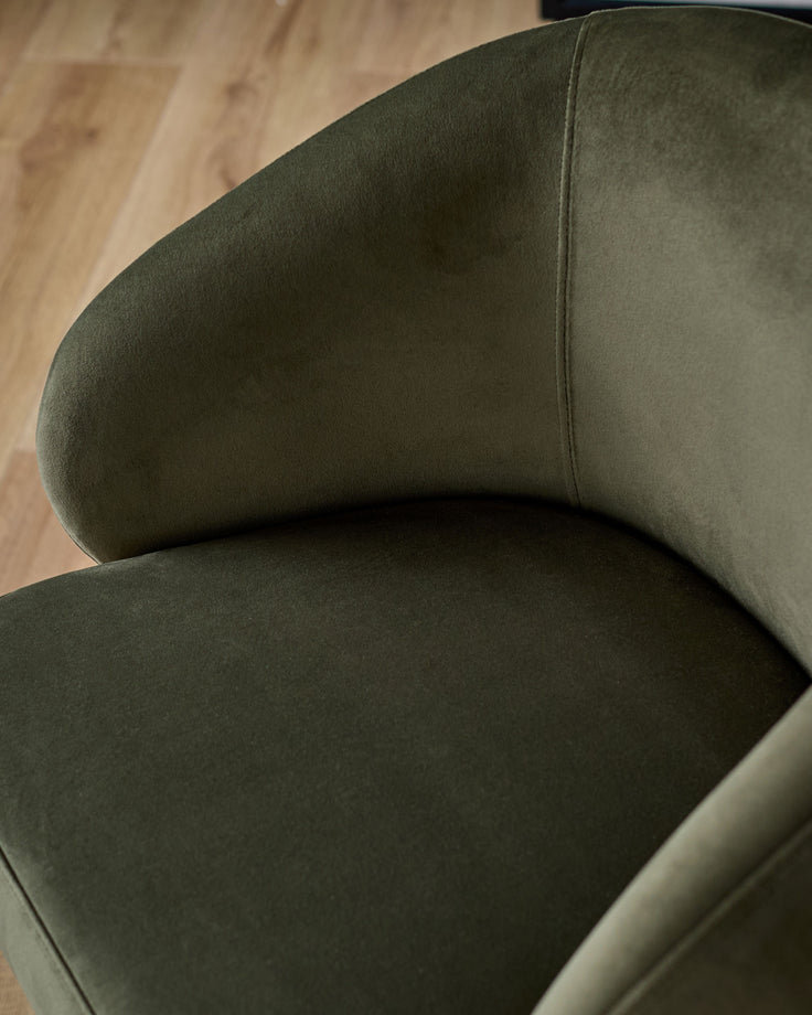 Darcy swivel dining chair in olive green velvet, showing curved backrest and seat from above angle on wooden floor.
