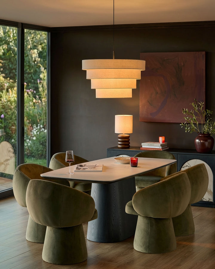 Darcy Swivel Dining Chair in olive green velvet, shown in a modern dining room setting around a wooden table.