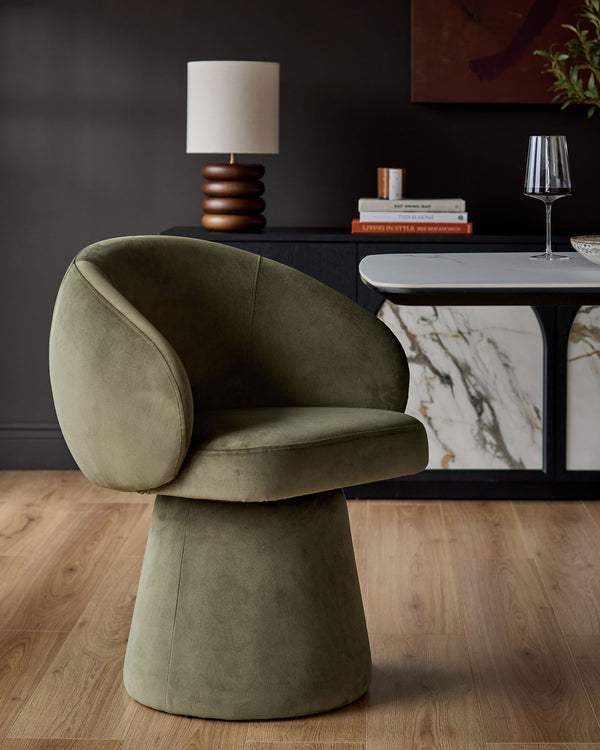 Darcy swivel dining chair in olive green velvet, featuring a rounded curved backrest and cylindrical base, shown in room setting.