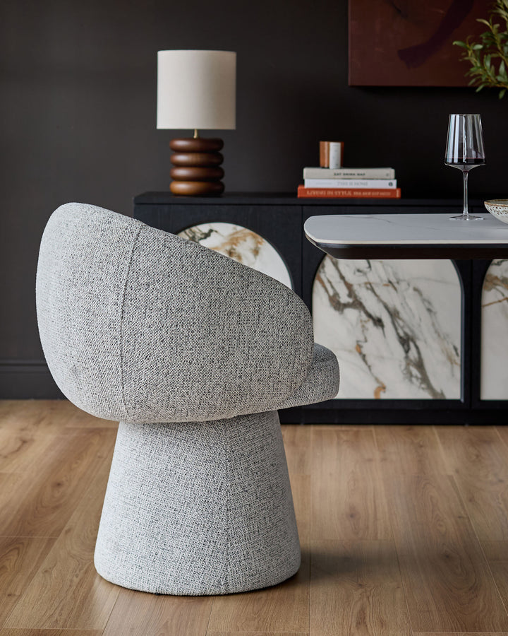 Darcy Swivel Dining Chair in grey fabric, shown from rear angle in a styled dining room setting.