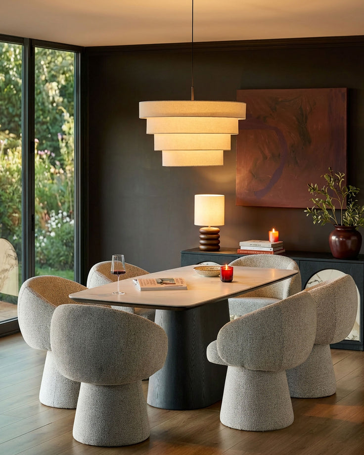Darcy swivel dining chair in grey fabric, shown in a styled dining room setting around a wooden table.