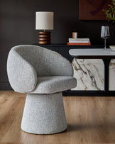 Darcy grey fabric swivel dining chair with curved back and pedestal base, shown in a styled room setting.